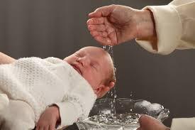 Lapsi, jota kastetaan. Käsi valuttaa vettä päähän.